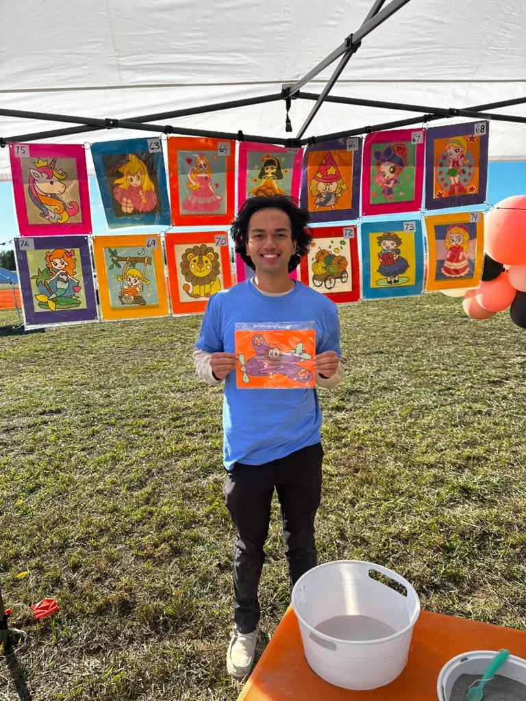 A young maker holding a colorful flower painting at a Nashville Crafting Club party.